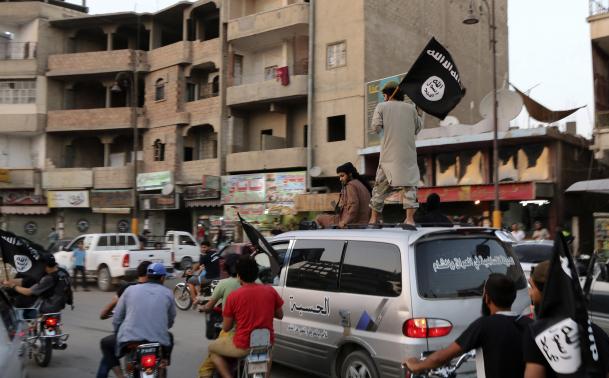 Members loyal to the ISIL wave ISIL flags as they drive around Raqqa