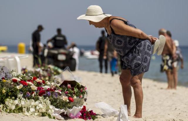 A tourist reads messages left at a makeshift memorial at the beach near the Imperial Marhaba resort, which was attacked by a gunman in Sousse, Tunisia, June 29, 2015. REUTERS/Zohra Bensemra